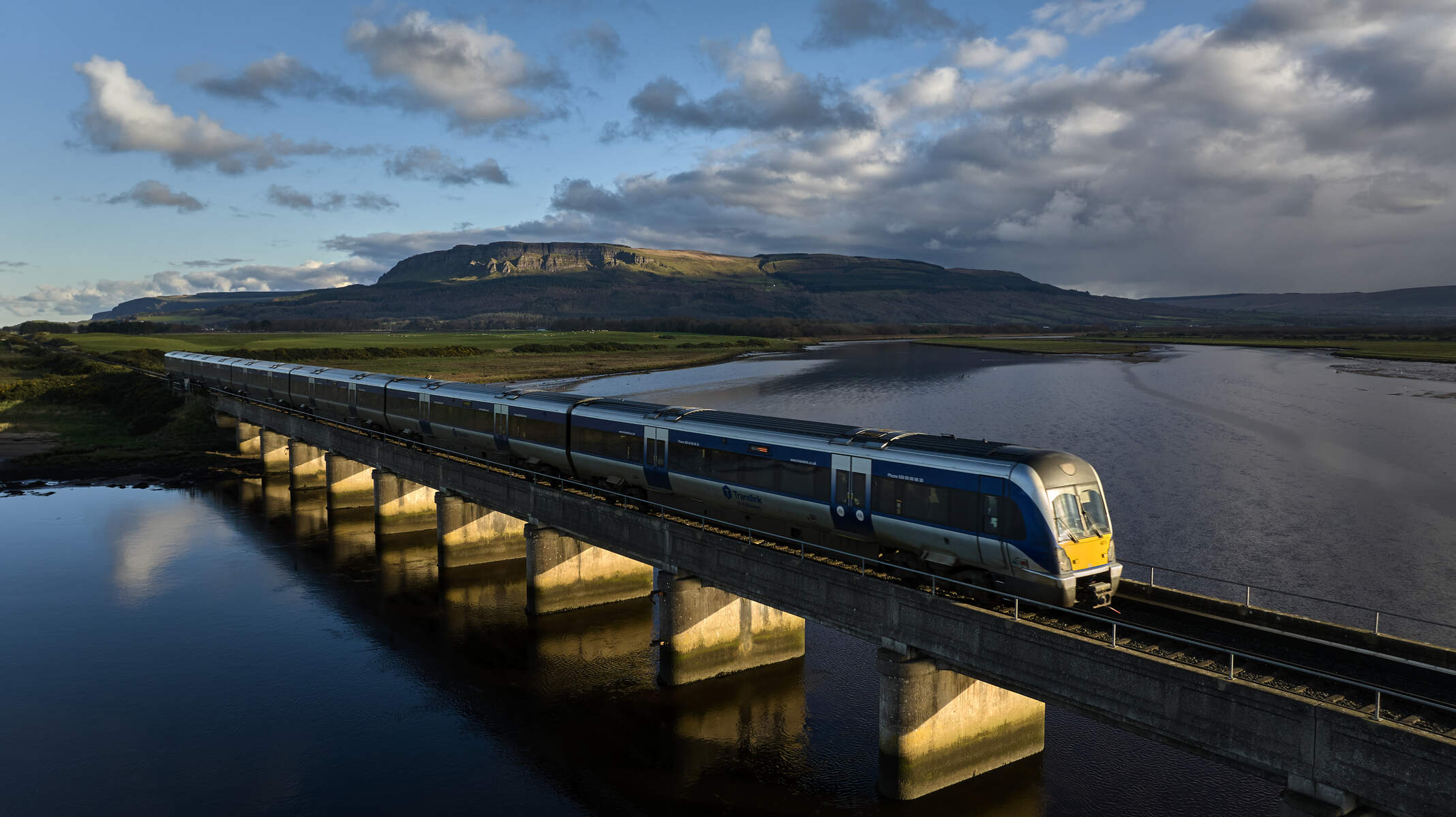 Train on railway crossing over River Roe near Binevenagh Mountain Co Londonderry